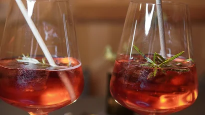 Zwei Gläser mit rotem Cocktail und Papierstrohhalmen auf einem Tisch