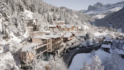 Winterlandschaft mit schneebedecktem Dorf und Bergen im Hintergrund