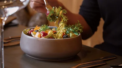 Person isst einen frischen gemischten Salat aus einem grauen Teller