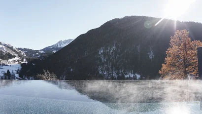 Dampfender Pool mit Bergblick bei Sonnenschein im Winter