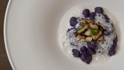 Elegantes Gericht mit lila Gnocchi, Pilzen und Schaum auf weißem Teller
