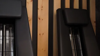 Zwei schwarze Massagestühle vor einer Wand mit Holzpaneelen