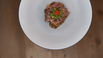 Gegrilltes Steak mit grüner Garnitur und Tomate auf weißem Teller