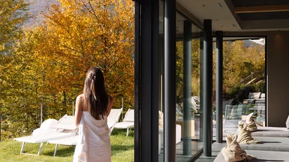 Frau mit Handtuch läuft zu Liegestühlen neben modernen Glasfenstern und Pool