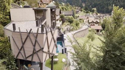Moderne Berghütte mit Garten und Blick auf bewaldete Berge und Dorf