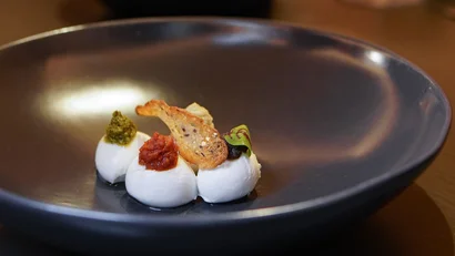 Drei Frischkäse-Portionen mit verschiedenen Soßen und Brotchip auf schwarzem Teller