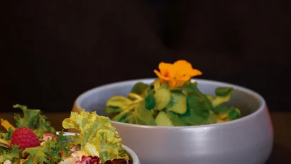 Zwei Schalen mit frischem grünen Salat und bunten Blättern auf Holztisch