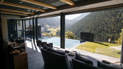 Moderner Innenraum mit Couch und Panoramablick auf Berglandschaft und Pool