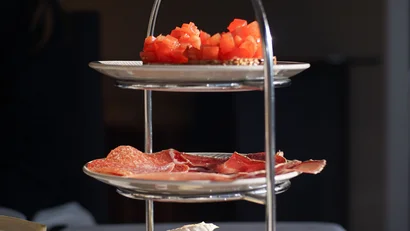 Dreistöckiges Tablett mit Käse, Wurst und Tomaten auf einem Tisch