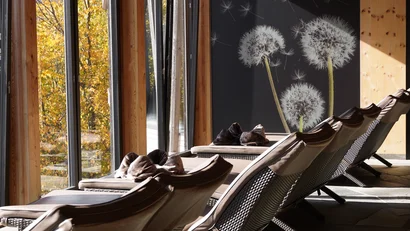 Ruheliegen in einem hellem Raum mit Holzbalken und Löwenzahnmotiv an der Wand