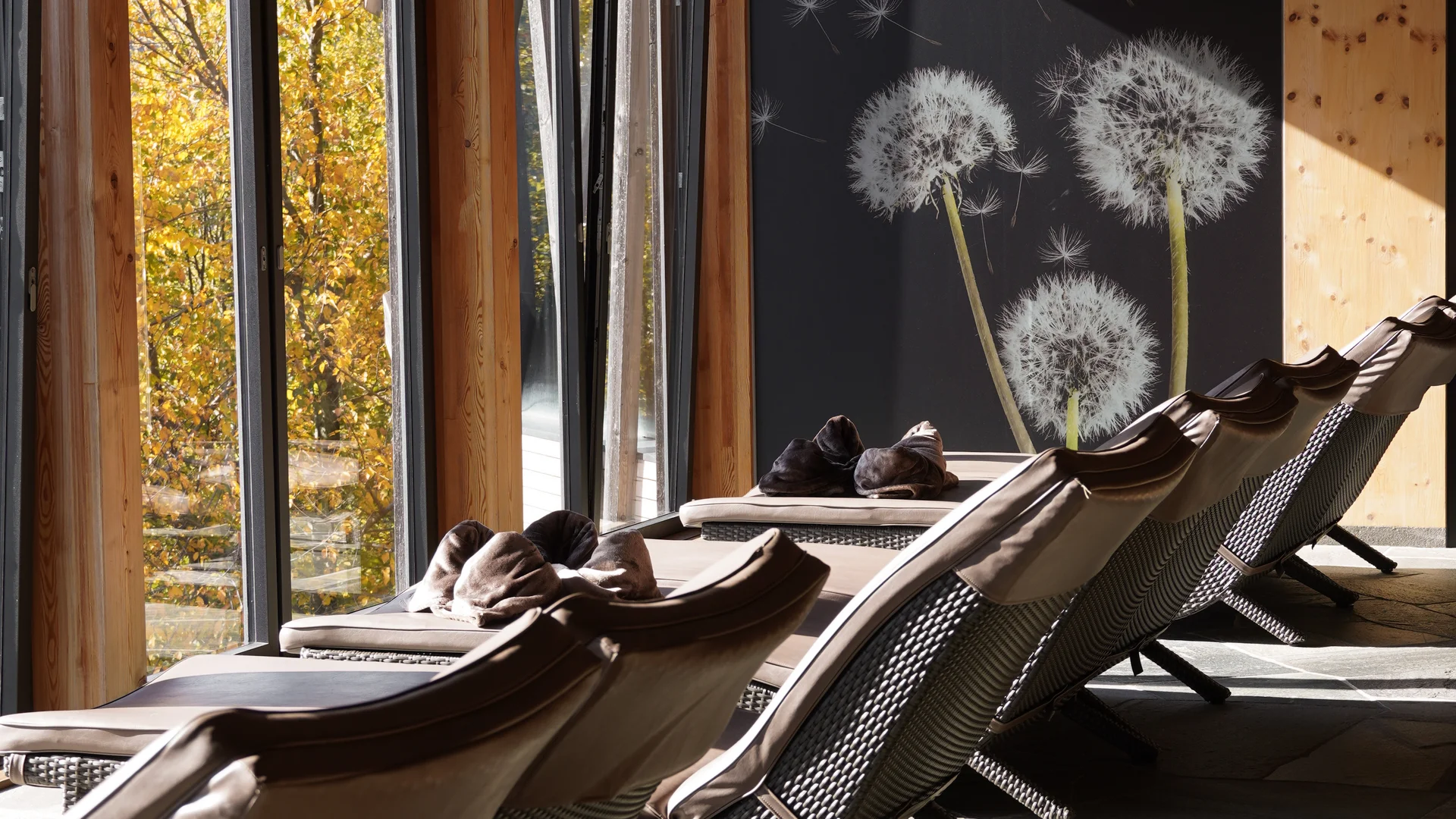 Ruheliegen in einem hellem Raum mit Holzbalken und Löwenzahnmotiv an der Wand