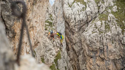 Kletterer in Schutzhelmen klettern durch eine enge Felsspalte in den Bergen