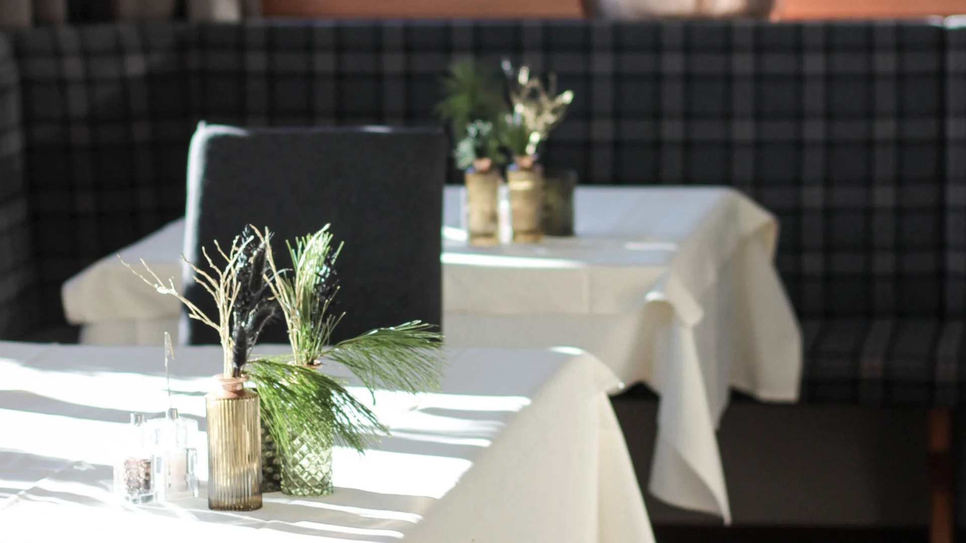 Sala da pranzo illuminata con tovaglie bianche e decorazioni verdi sui tavoli